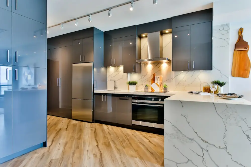 Modern kitchen with grey cabinets, marble countertops, and light wood flooring, illustrating cooperative and shared housing
